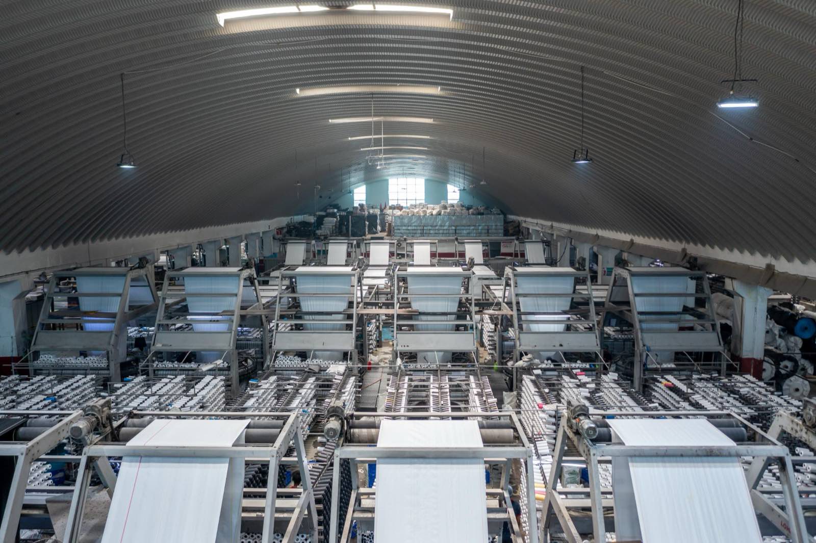 Loom hall — rows of circular looms under the arched roof