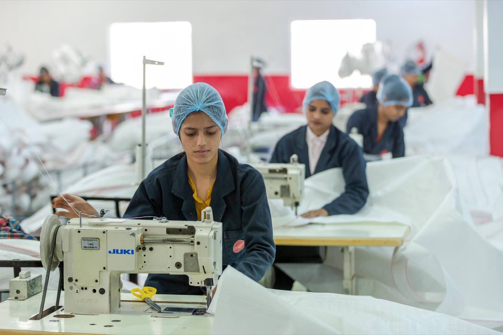Women operating industrial sewing machines on the Pegma FIBC finishing line